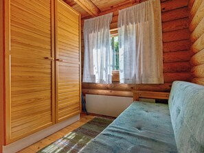 Una habitación tipo cabaña de madera con un armario de madera, una ventana con cortinas y un sofá.