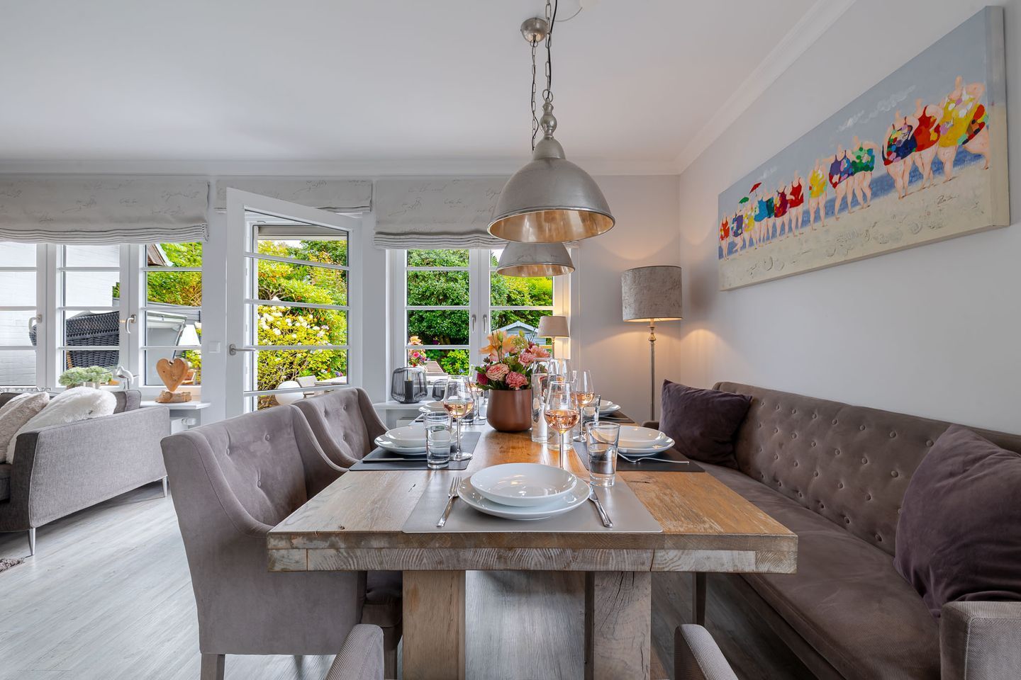 A dining area with a wooden table, grey upholstered chairs, and a modern pendant light.