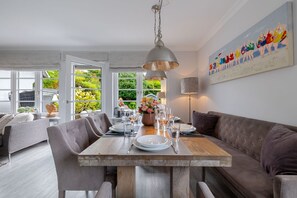 A dining area with a wooden table, grey upholstered chairs, and a modern pendant light. - Hedigen Hüs - Our Hedigen Hüs impresses with its consistent furnishings in the Sylt style. (Sylt)