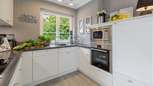 A modern kitchen with white cabinets, a Bosch oven, a microwave, and a sink. - Hedigen Hüs - Our Hedigen Hüs impresses with its consistent furnishings in the Sylt style. (Sylt)