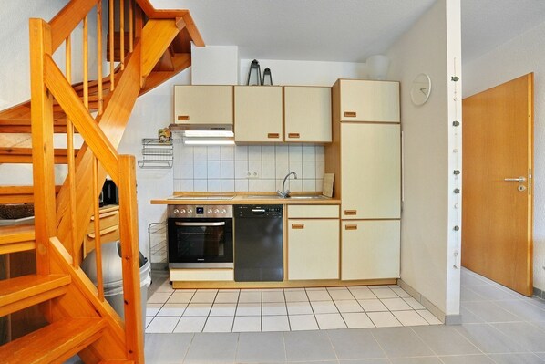 Una cucina compatta con mobili in legno, forno integrato e lavastoviglie.