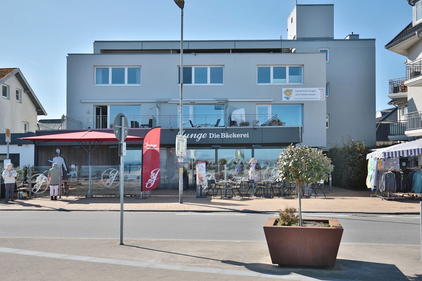 A modern building with a sign for 'Junge Die Bäckerei' and outdoor seating.