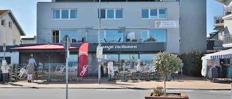A modern building with a sign for 'Junge Die Bäckerei' and outdoor seating.