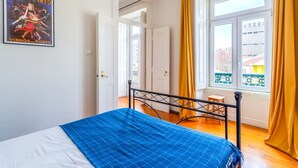 A bedroom with a bed, a window with yellow curtains, and a poster on the wall. - Cozy Lisbon Stay - 2 Min Walk from Av. Liberdade by Lisbeyond (Lisboa)