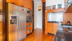 A modern kitchen with stainless steel appliances, wooden cabinets, and a black countertop. - Cozy Lisbon Stay - 2 Min Walk from Av. Liberdade by Lisbeyond (Lisboa)
