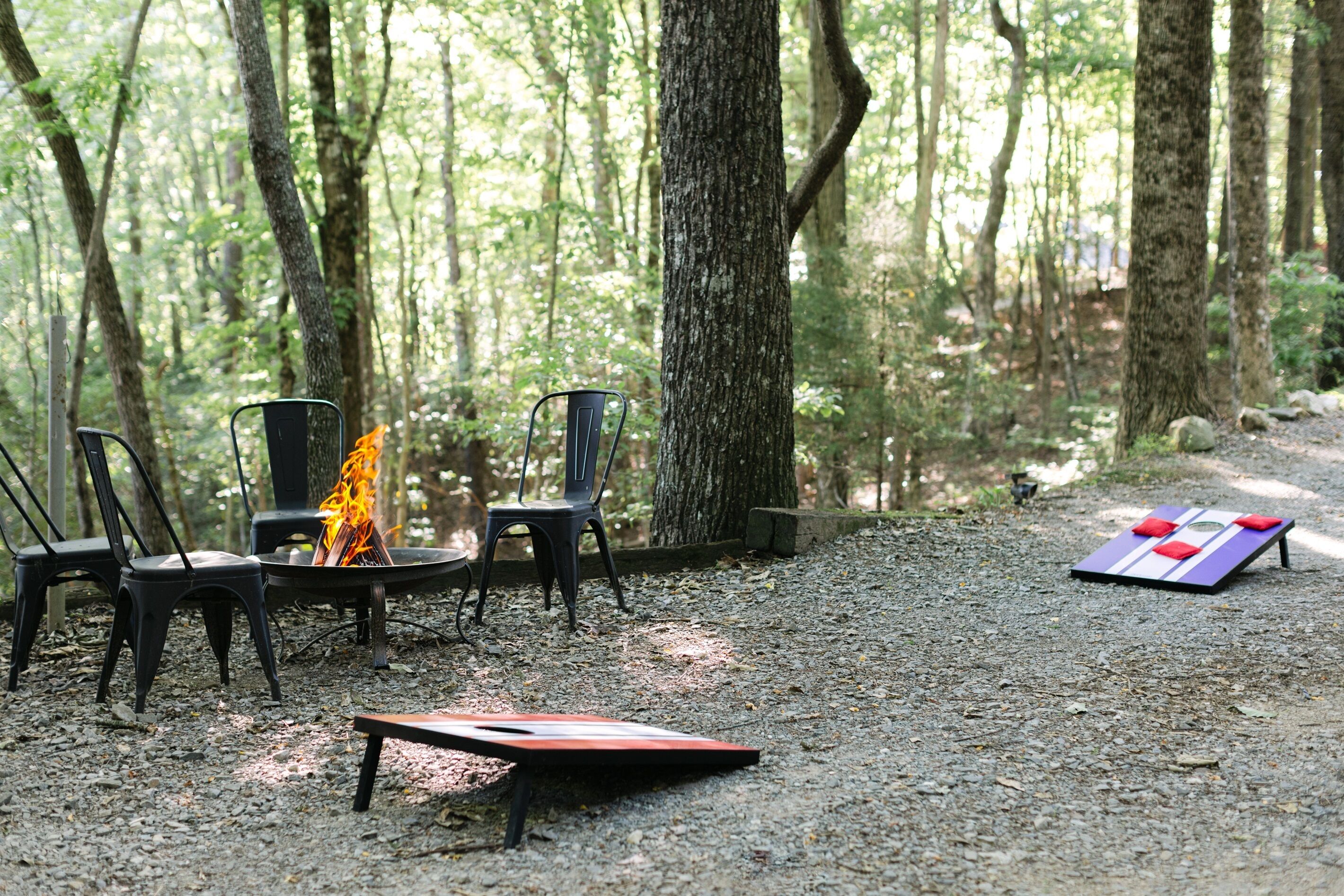 A campsite with chairs, a fire pit, and a board game.
