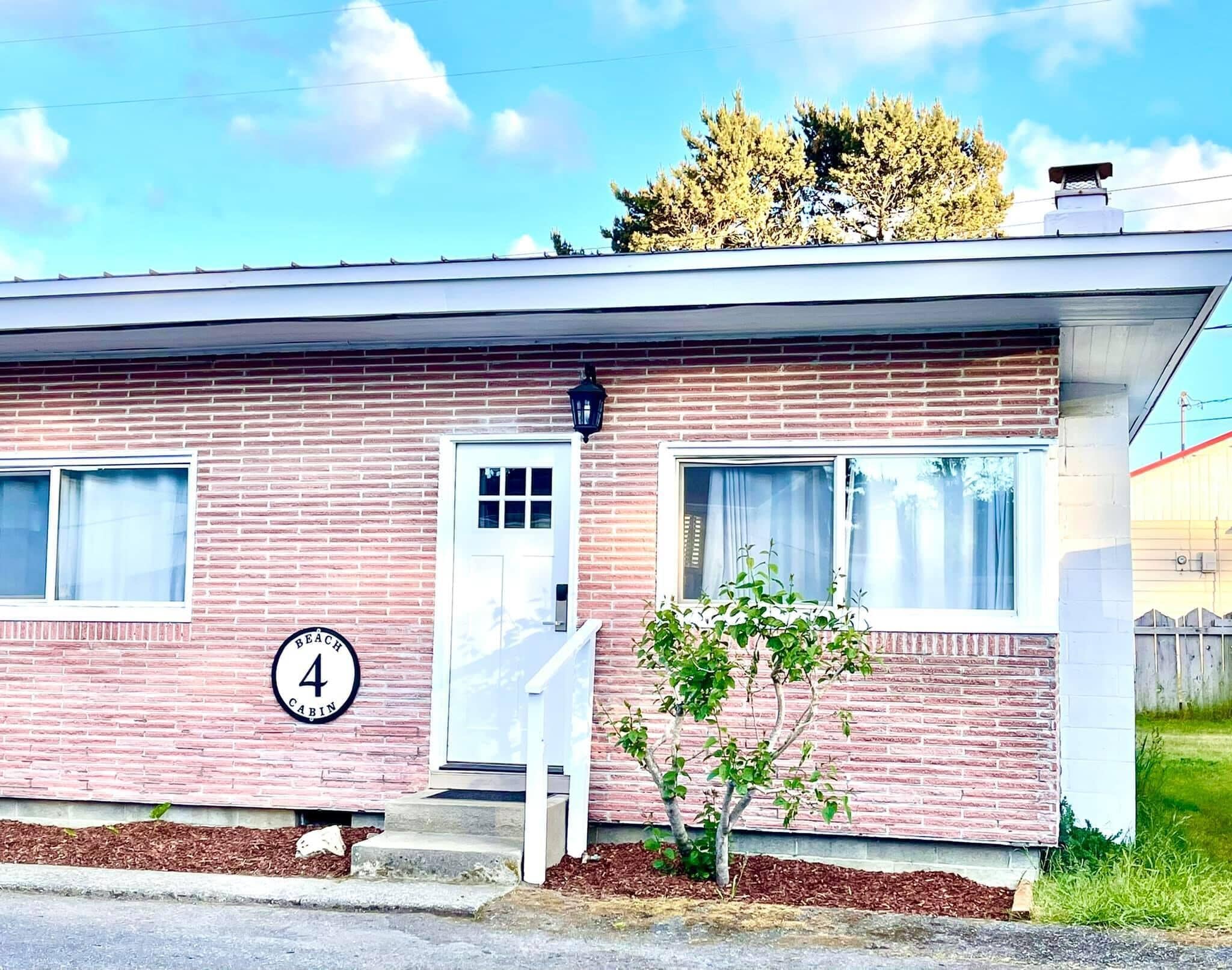 A single-story brick building with a white door and windows, a small porch, and a number '4' sign.