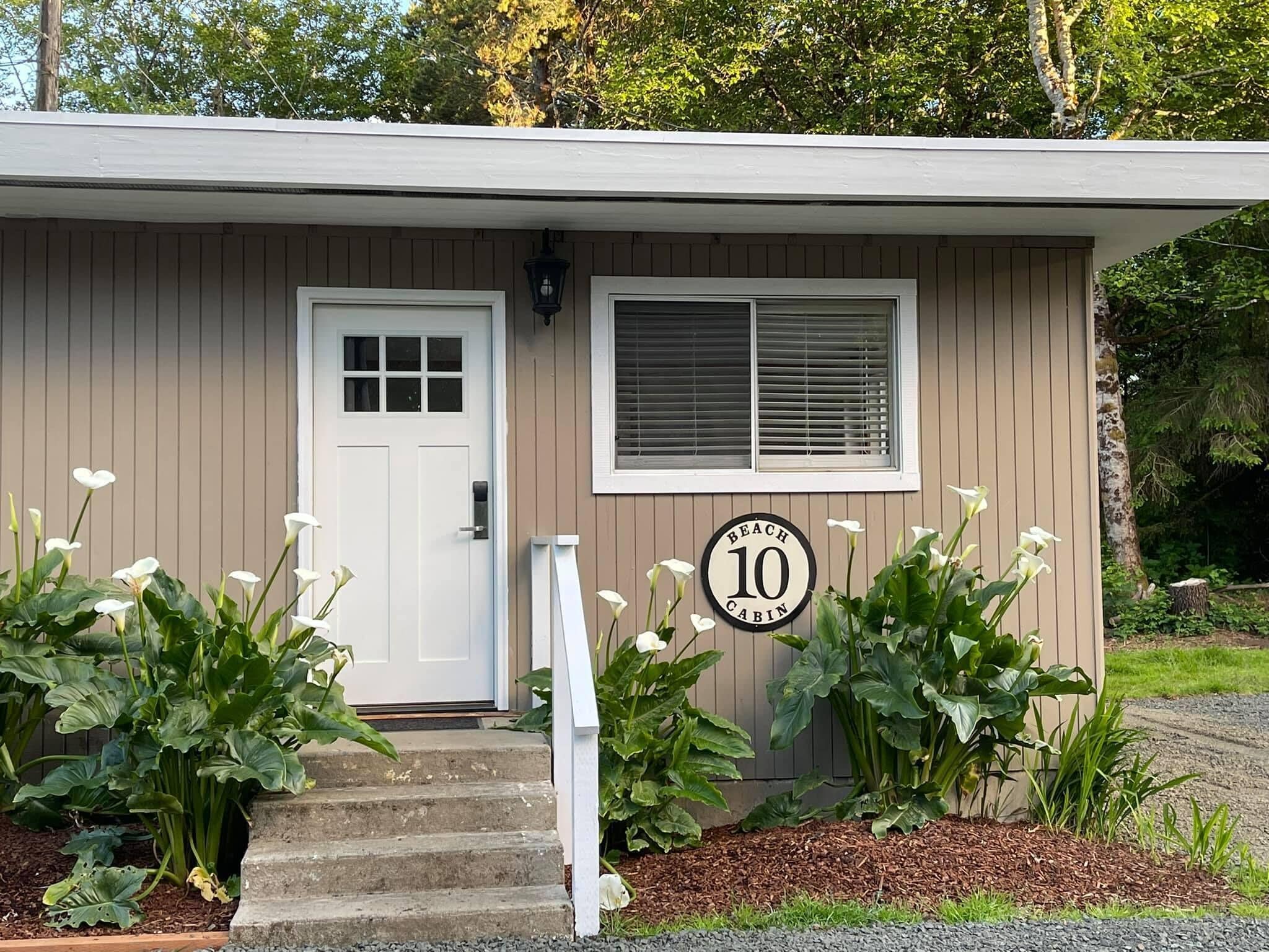 A small building with a white door, a window with blinds, and a sign indicating it is a '10 Cabin'.