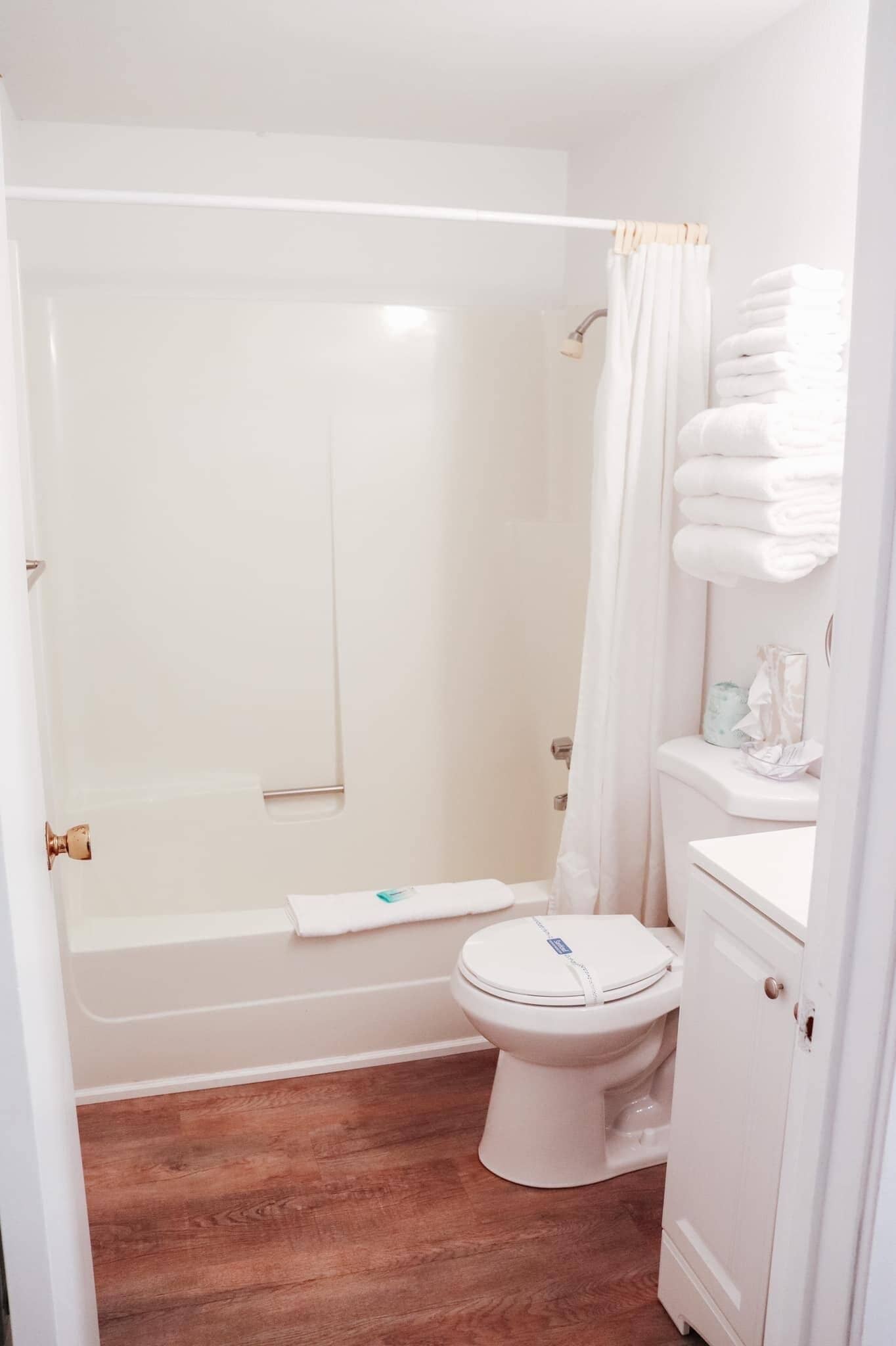A bathroom with a shower, toilet, and a cabinet with towels.