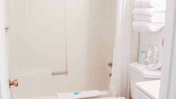 A bathroom with a shower, toilet, and a cabinet with towels.