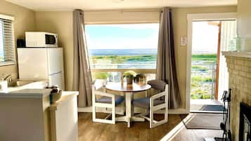 Cocina compacta con microondas, lavamanos y comedor con vista al océano.