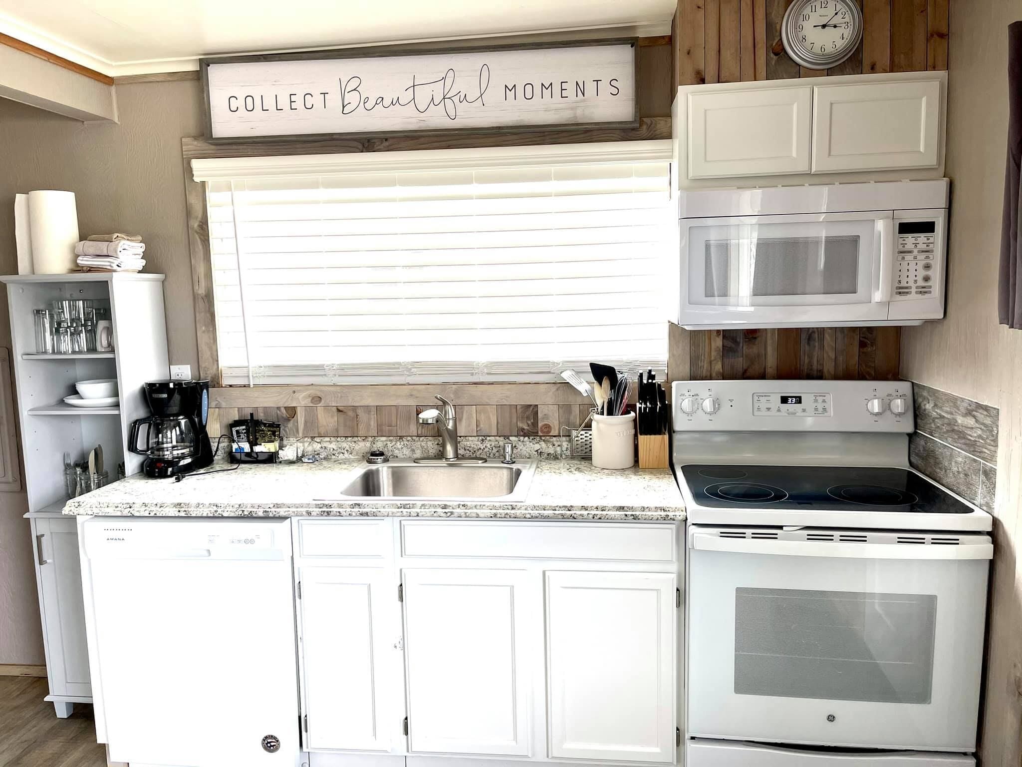 A kitchen with white cabinets, a stainless steel sink, a built-in oven, a microwave, and a coffee maker.