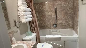 A bathroom with a bathtub, toilet, sink, and a towel rack with folded towels.