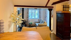 Una habitación acogedora con suelo de madera, una cama, un armario de madera oscura y una ventana con cortinas.