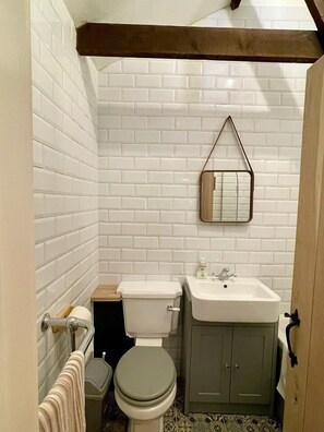 A small, compact bathroom with white tiled walls, a toilet, a sink, and a cabinet. - Charming 2-Bed Lodge in Dorchester (Dorchester)