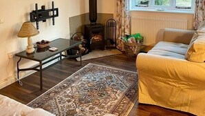 Una sala de estar acogedora con chimenea, un sofá, una mesa con lámpara y una ventana con cortinas.