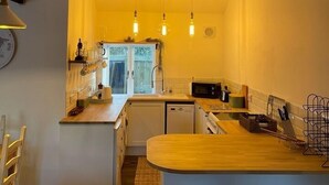 Cocina compacta con encimera de madera, lavavajillas integrado y lámparas colgantes.