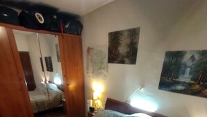 Un dormitorio con cama, mesita de noche, espejo y un cuadro en la pared.