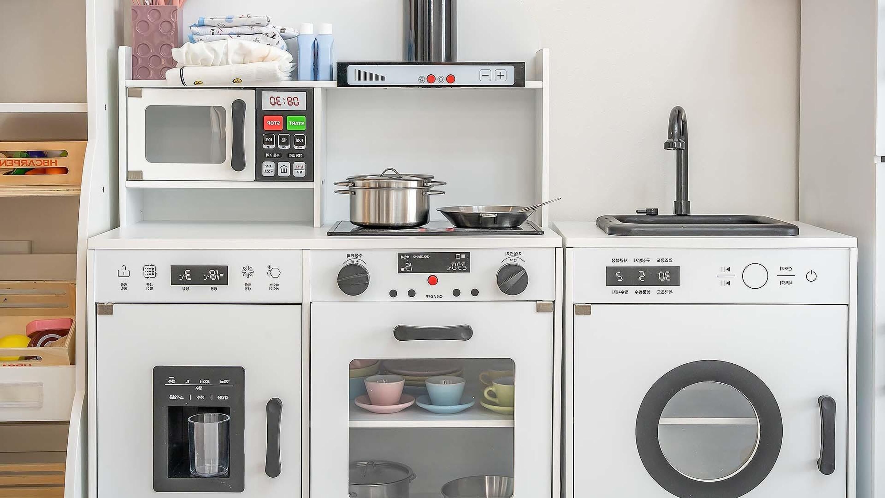 A compact kitchen setup with a microwave, stove, oven, and sink, featuring various kitchen utensils and cookware.