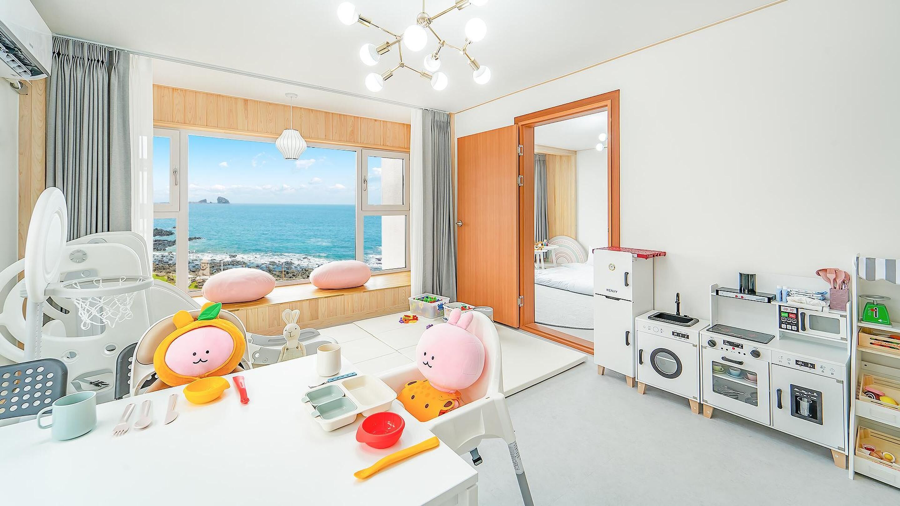 A child's playroom with a view of the sea, a kitchenette, and a large window.