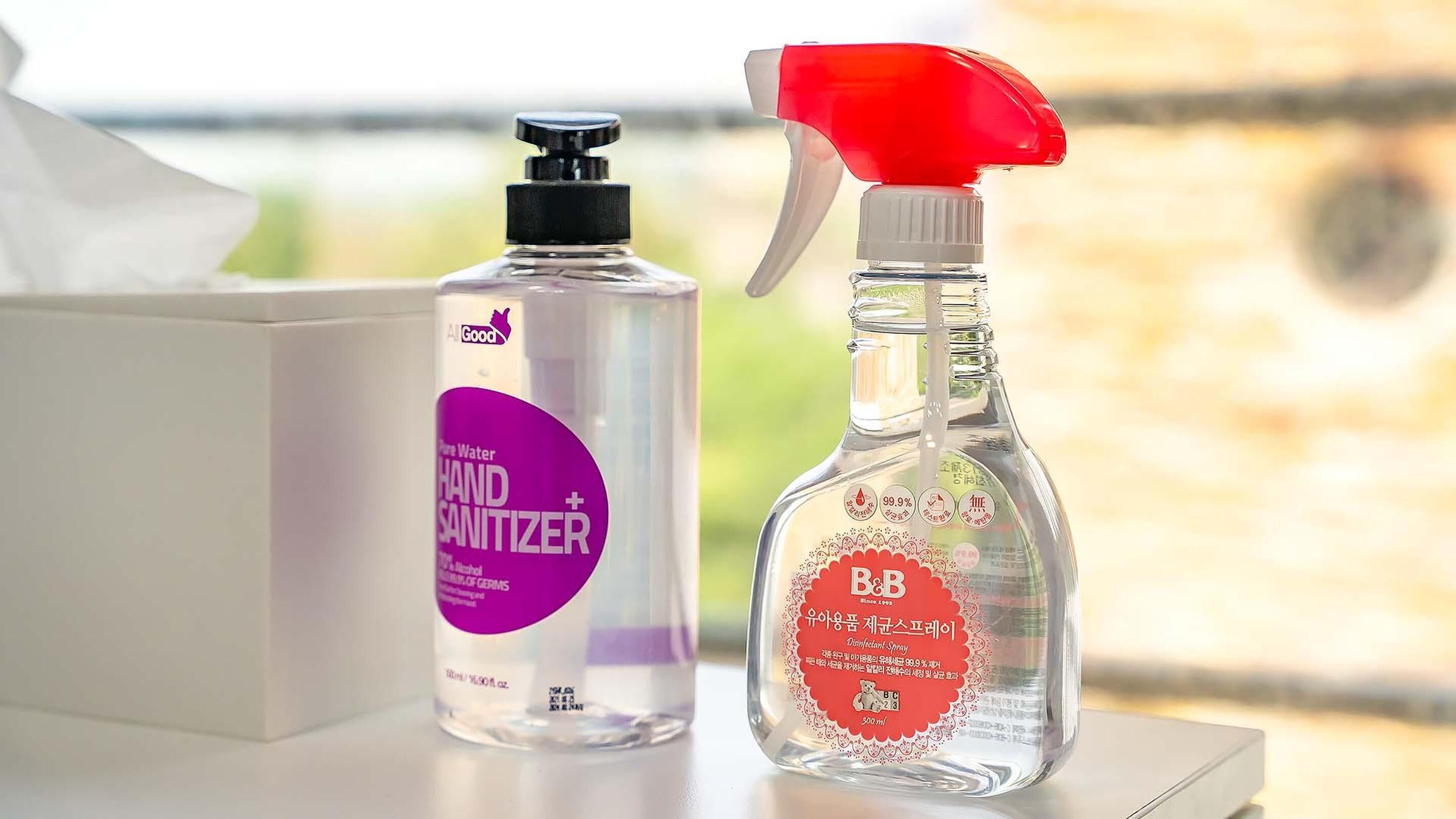 Due flaconi di gel disinfettante e una bottiglia spray su un tavolo.