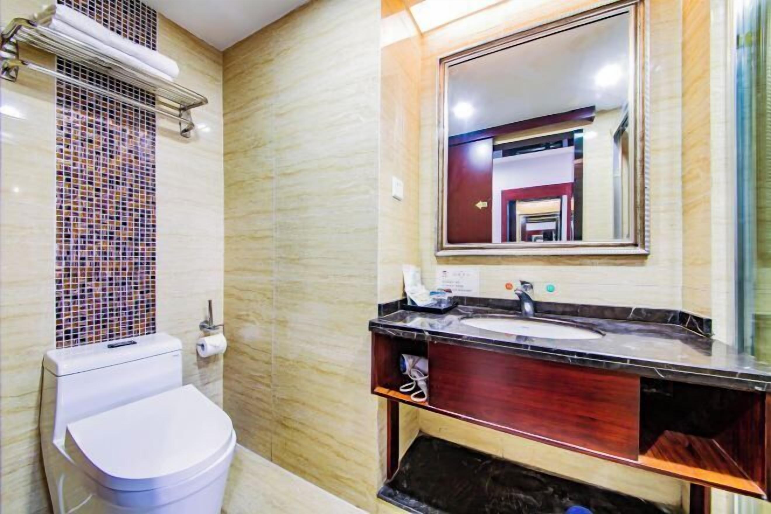 Un bany amb vàter, un lavabo amb mirall i una paret amb rajoles.