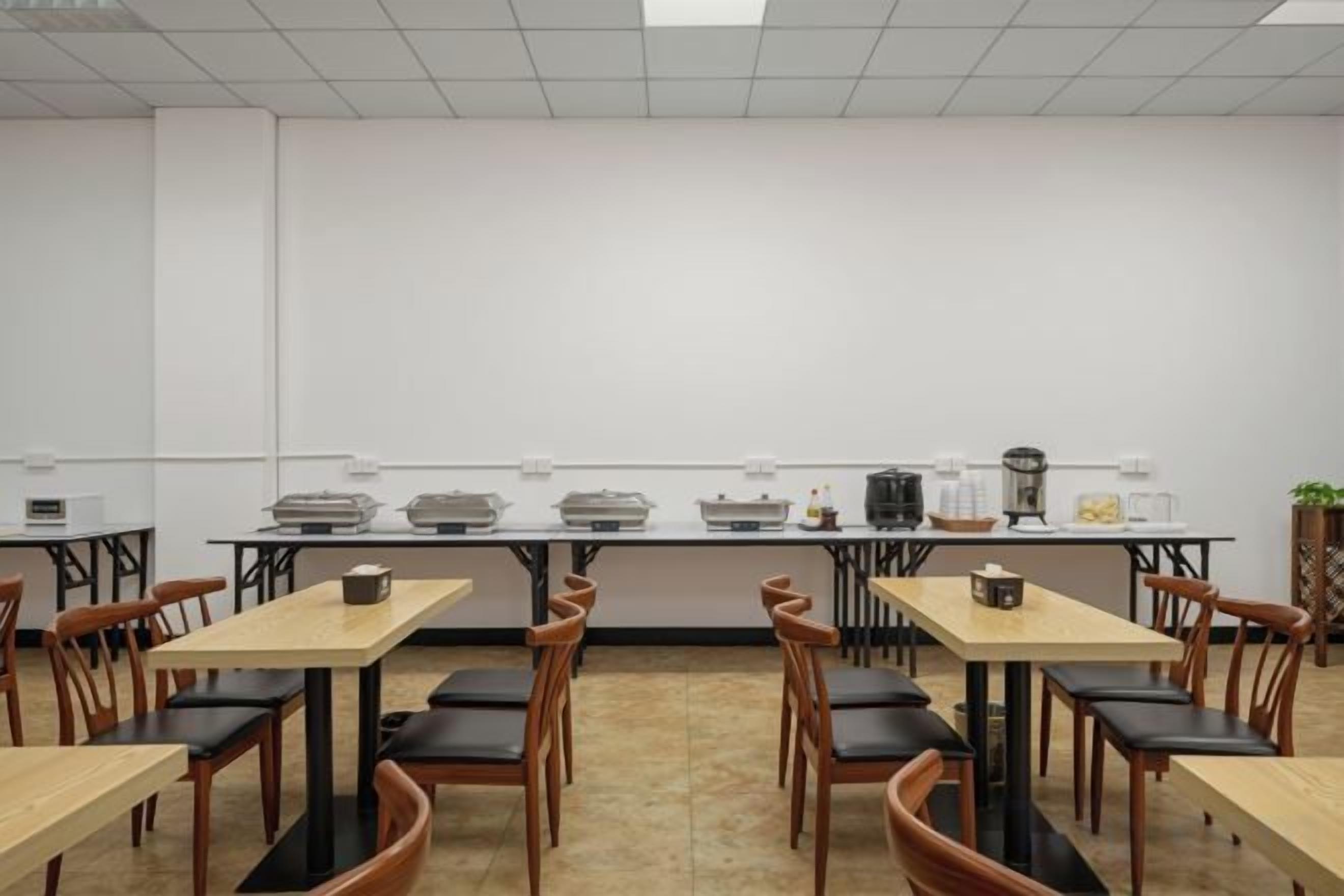 Un salón de conferencias con varias mesas y sillas, equipado con máquinas de café y otros servicios.