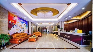 A hotel lobby with a reception desk, plush seating, a chandelier, and a large wall mural.