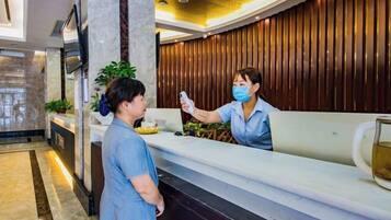 A reception area with a marble counter, a wooden panel wall, and a plant.