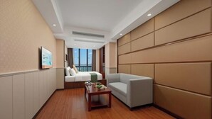 A hotel room with a bed, a sofa, a small table, and a view of the outdoors.