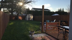 A backyard with a wooden deck, a shed, and a lawn.