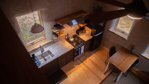 Une cuisine compacte dotée d’un îlot central, d’une table à manger et de deux fenêtres qui laissent entrer la lumière naturelle.