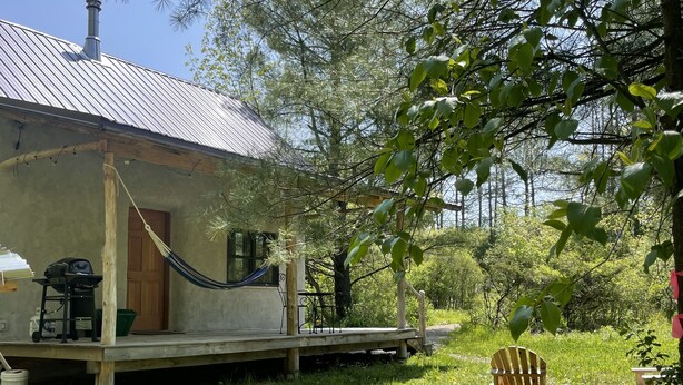 Un chalet rustique avec un toit en métal, un hamac et une terrasse en bois.