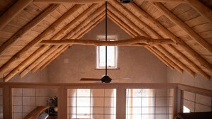 Une pièce avec un haut plafond en bois, une fenêtre visible et un ventilateur de plafond.