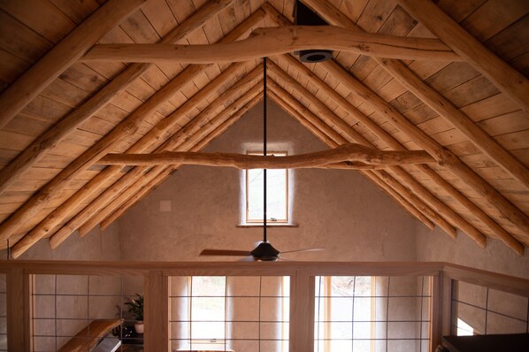 Een kamer met hoog houten plafond, een zichtbaar raam en een plafondventilator.