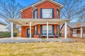 A two-story house with a covered porch and a front yard.