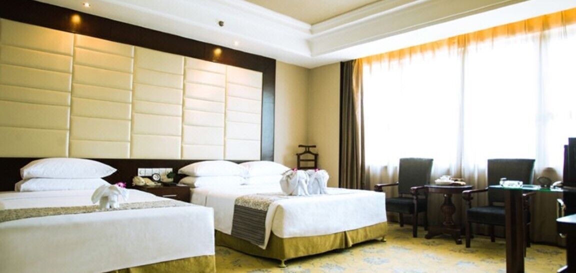A hotel room with two beds, a desk, and a chair.