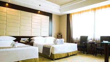A hotel room with two beds, a desk, and a chair.