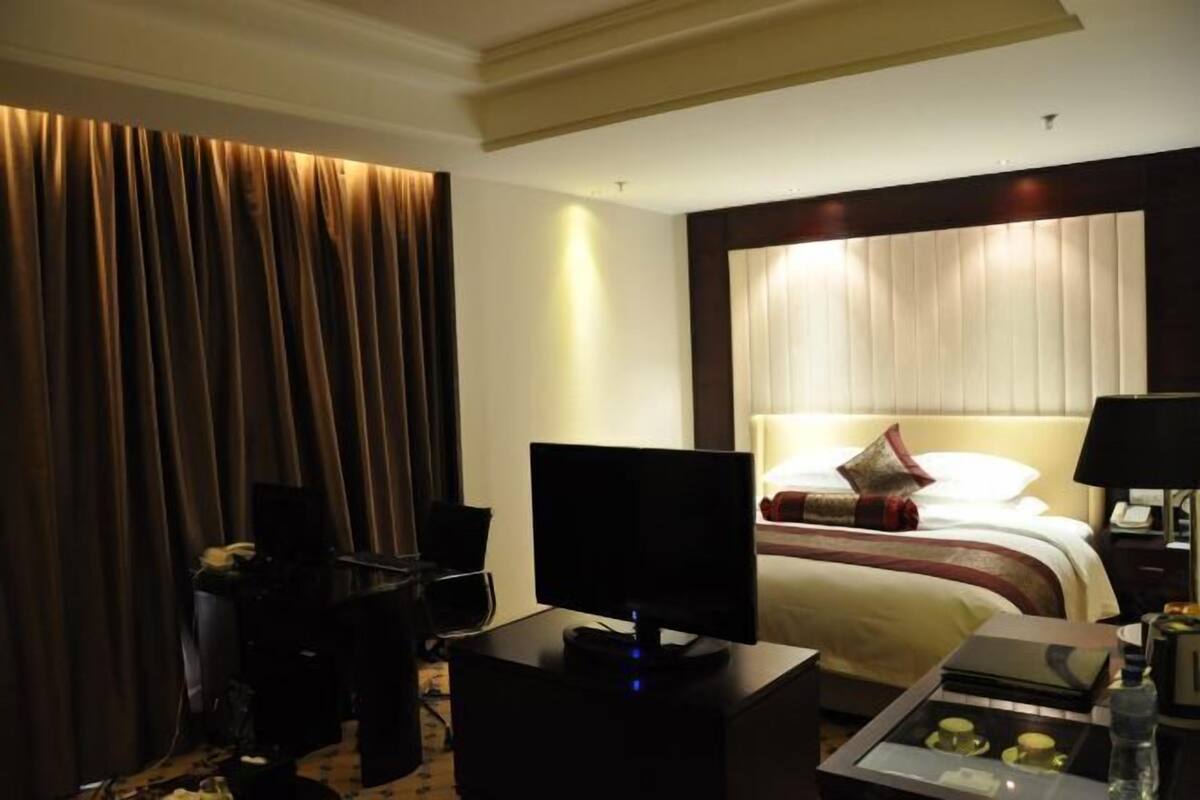 Una habitación de hotel con cama, televisión, escritorio y silla.