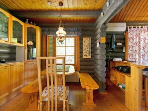 A cozy cabin interior with a wooden dining table, bench, and a hanging light fixture. - Sinisorsa by Interhome (Joutsa)