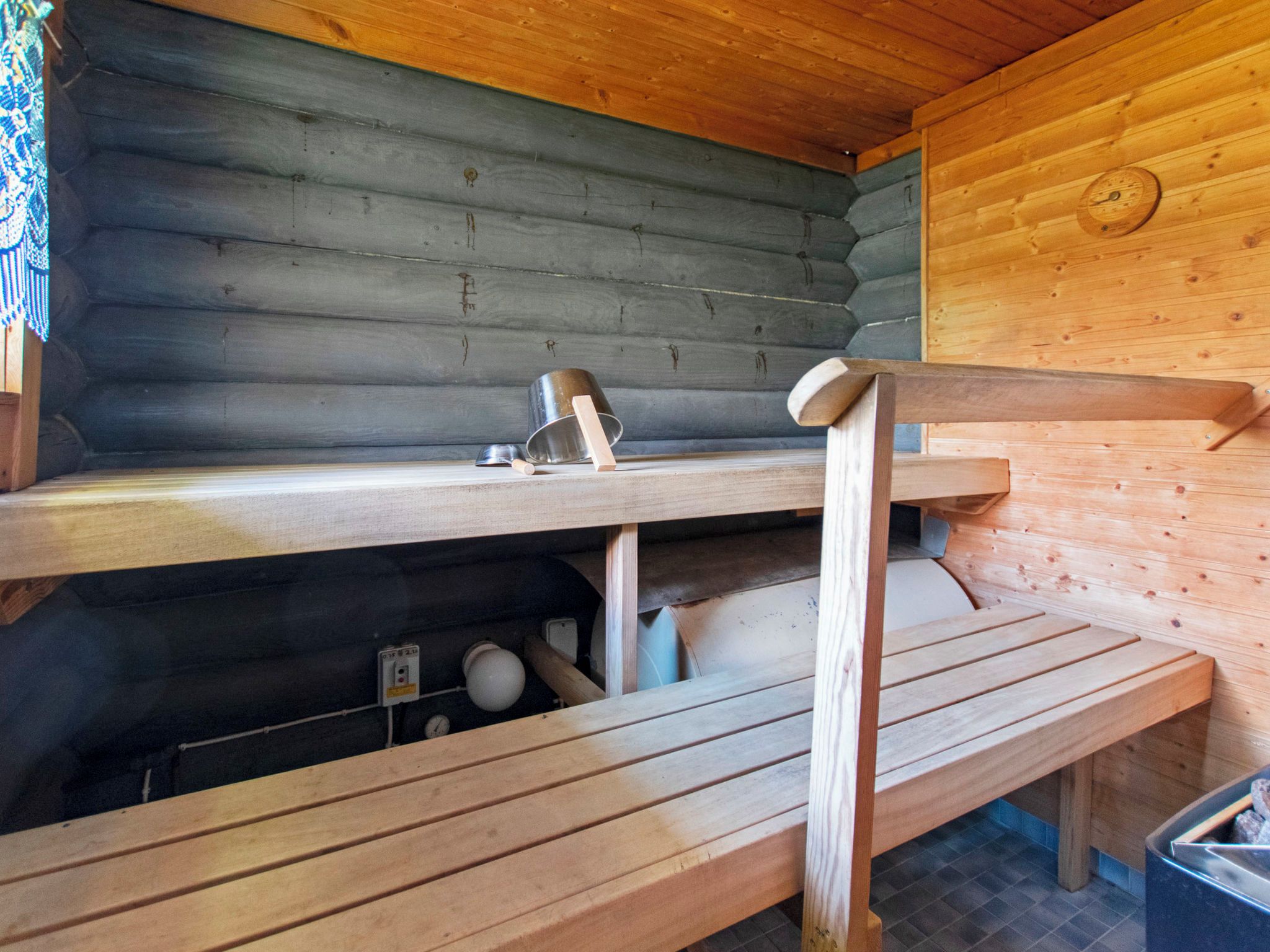 A wooden bench with a metal bucket and a wooden spoon on a bench top.