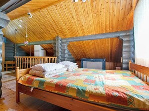 Une chambre à coucher située dans un chalet en bois, avec un lit, des oreillers, une courtepointe, une chaise en bois et une petite table.