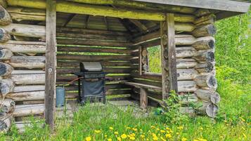 Une cabane en bois rustique, avec un barbecue et un distributeur d’eau à l’extérieur.