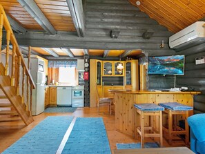 A cabin interior with a kitchen, dining area, and a living space with a TV.