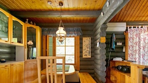 Un interior de cabaña acogedor con muebles de madera, una mesa de comedor y un banco.
