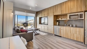 Eine moderne Küche mit Holzausstattung, einer eingebauten Mikrowelle und einem Essbereich mit Tisch und Sofa.