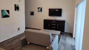 A modern living room with a ceiling fan, a flat-screen TV, a sofa, and artwork on the walls. - #204 New Beautiful Modern Condo Downtown Monroe! (Monroe)