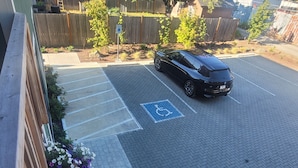A parking lot with a designated handicapped parking space, a BMW parked in the lot, and a wooden fence in the background. - #204 New Beautiful Modern Condo Downtown Monroe! (Monroe)
