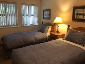 A bedroom with two single beds, a nightstand with a lamp, and a framed picture on the wall.