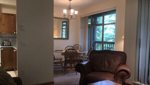 Ein Wohnzimmer mit einem braunen Ledersessel, einem Holztisch und einem Essbereich mit Holztisch und Stühlen.